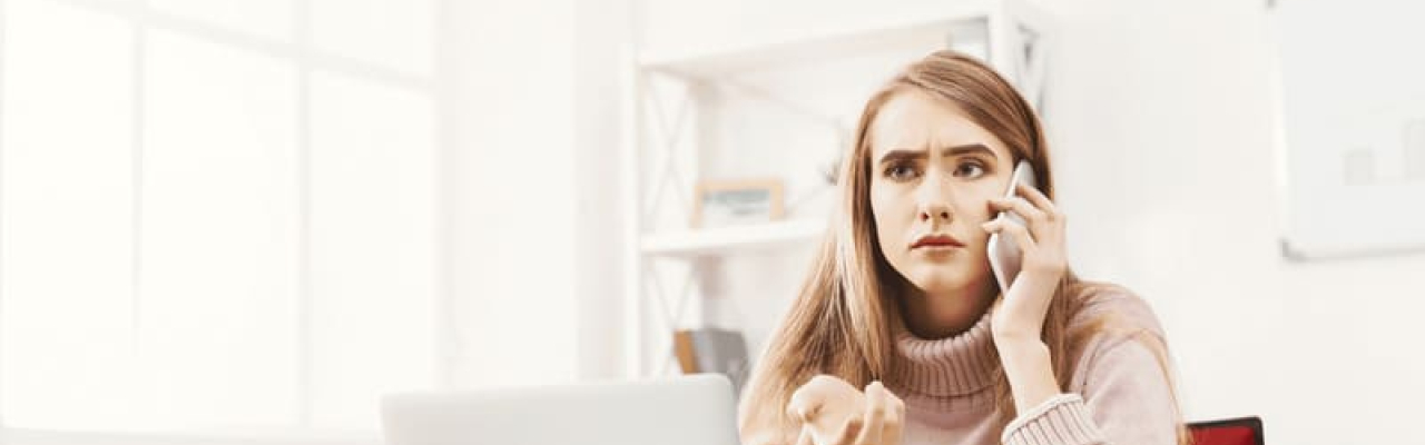 femme mécontente au téléphone devant son ordinateur assise dans son bureau