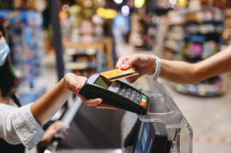 Femme qui règle ses achats dans un supermarché avec sa carte de paiement sans contact