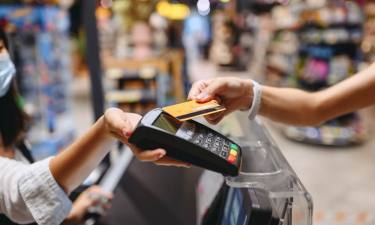 Femme qui règle ses achats dans un supermarché avec sa carte de paiement sans contact