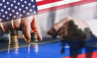 une main soulève une pile de pièces sur fond de drapeau des états-unis